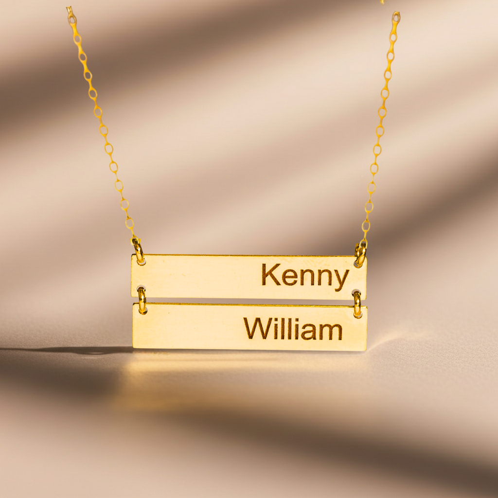 Gold necklace with engraved names 'Kenny' and 'William' on a beige background